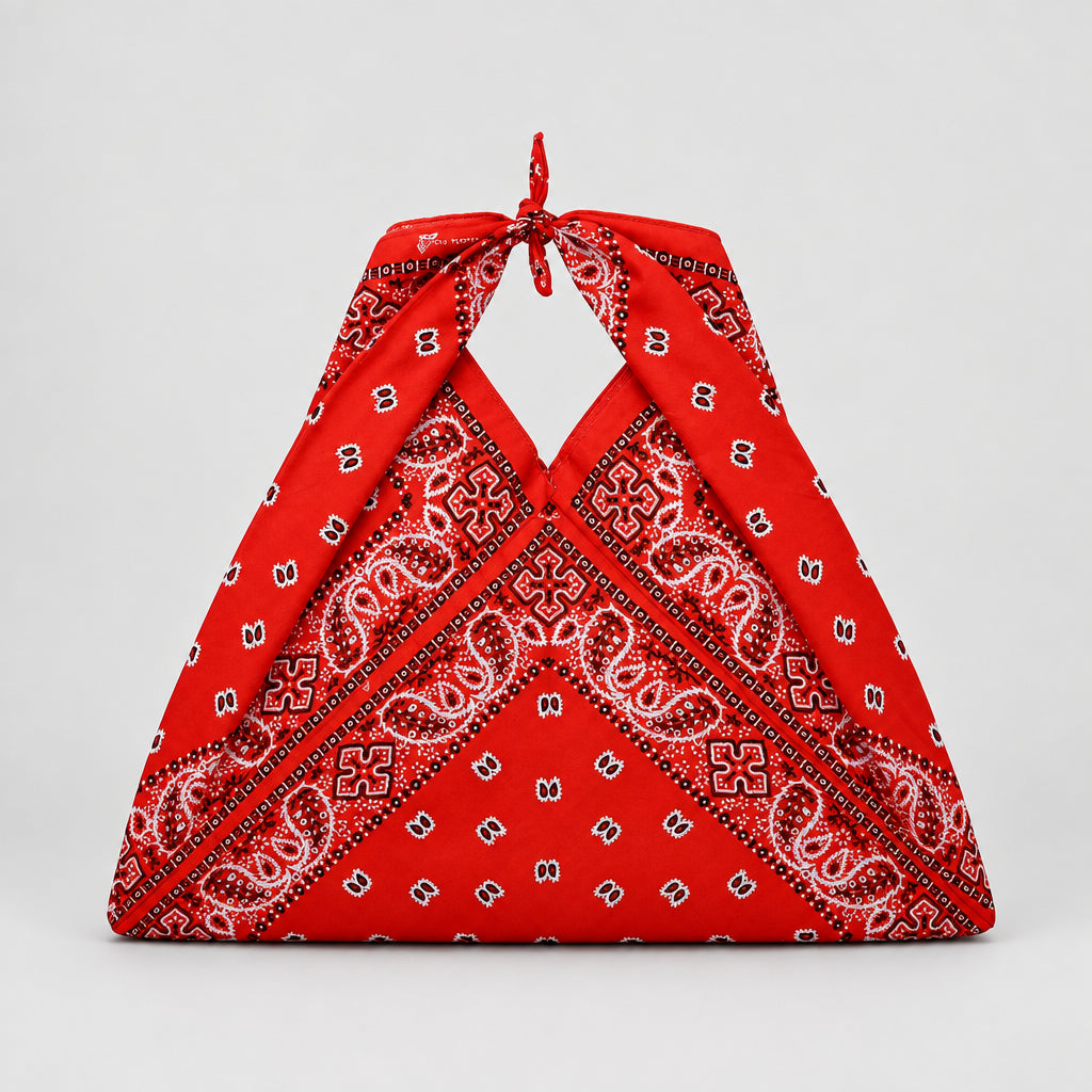 A red halter-style bag made from a paisley bandana fabric, featuring a tie-neck design and a small white label at the center front